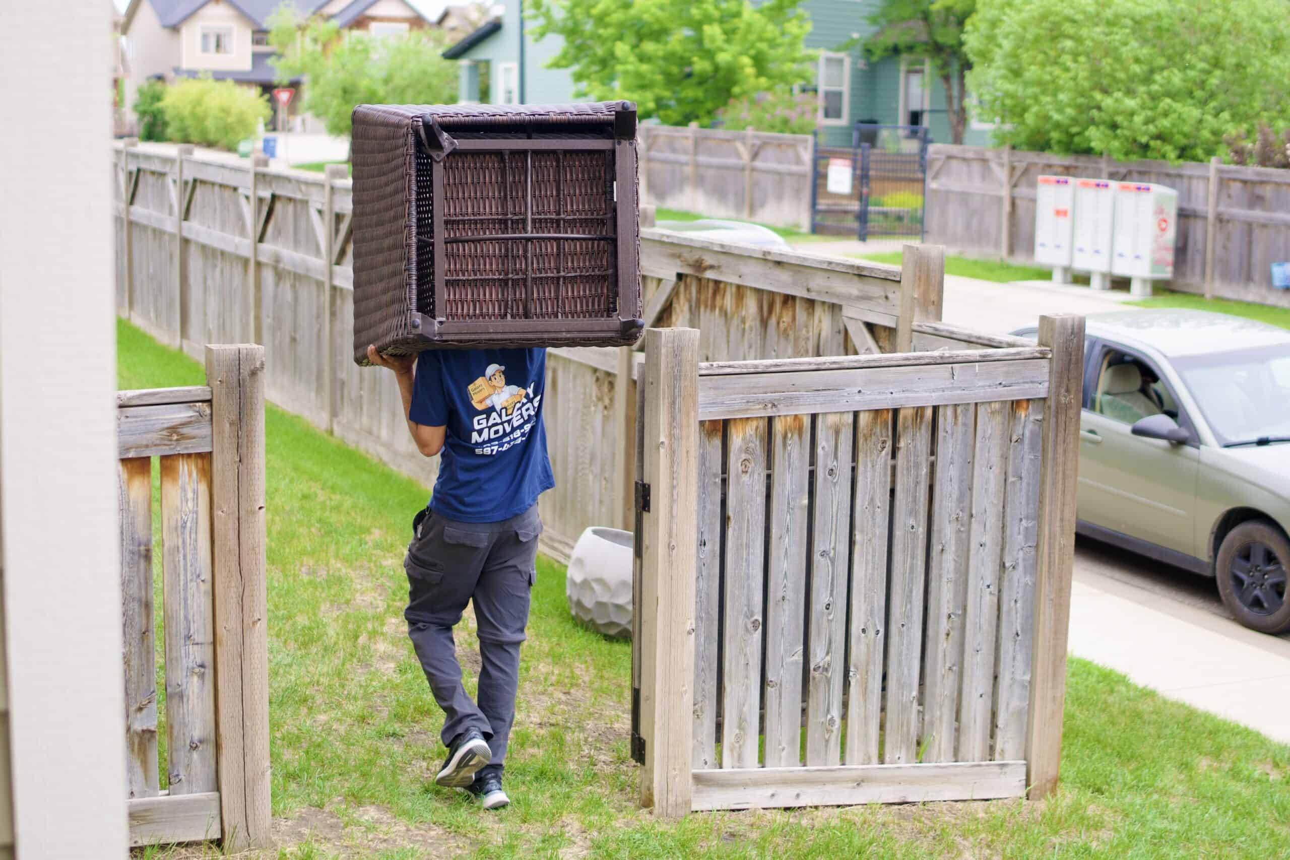 Mover carrying a large basket through a backyard gate in Beaumont