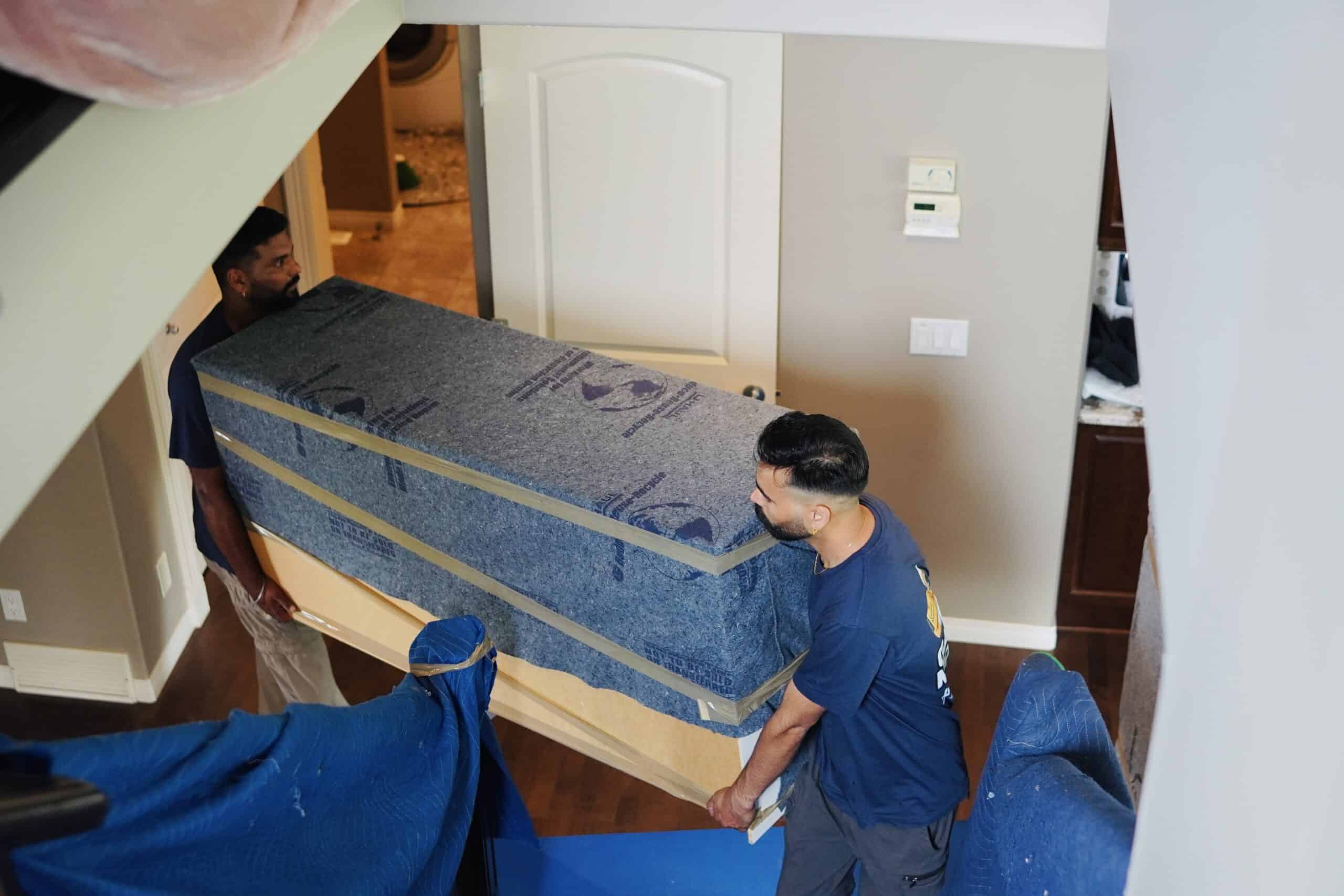 Movers transporting a large mattress into a home in Calgary