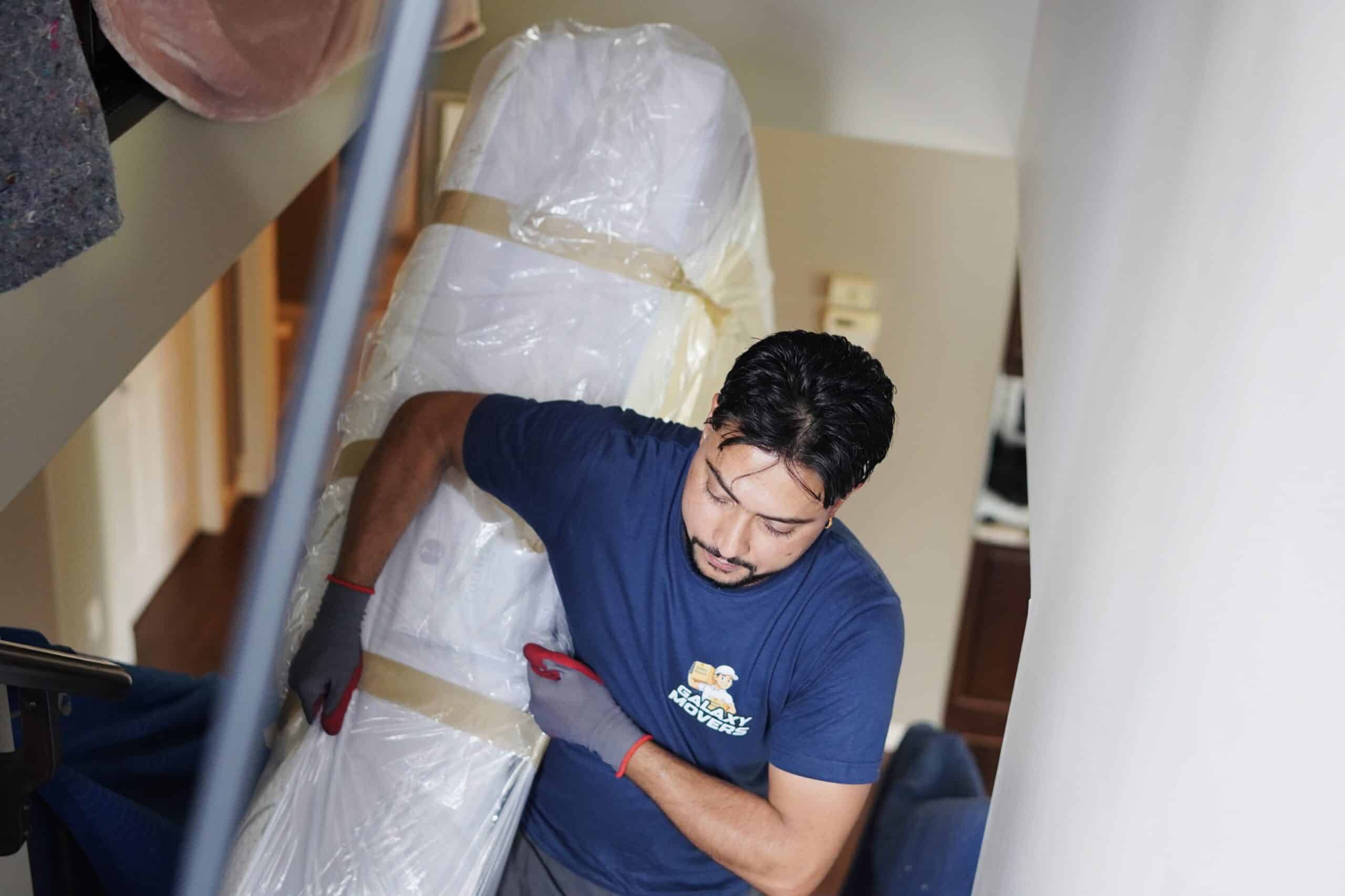 Mover carrying large wrapped furniture in Calgary home