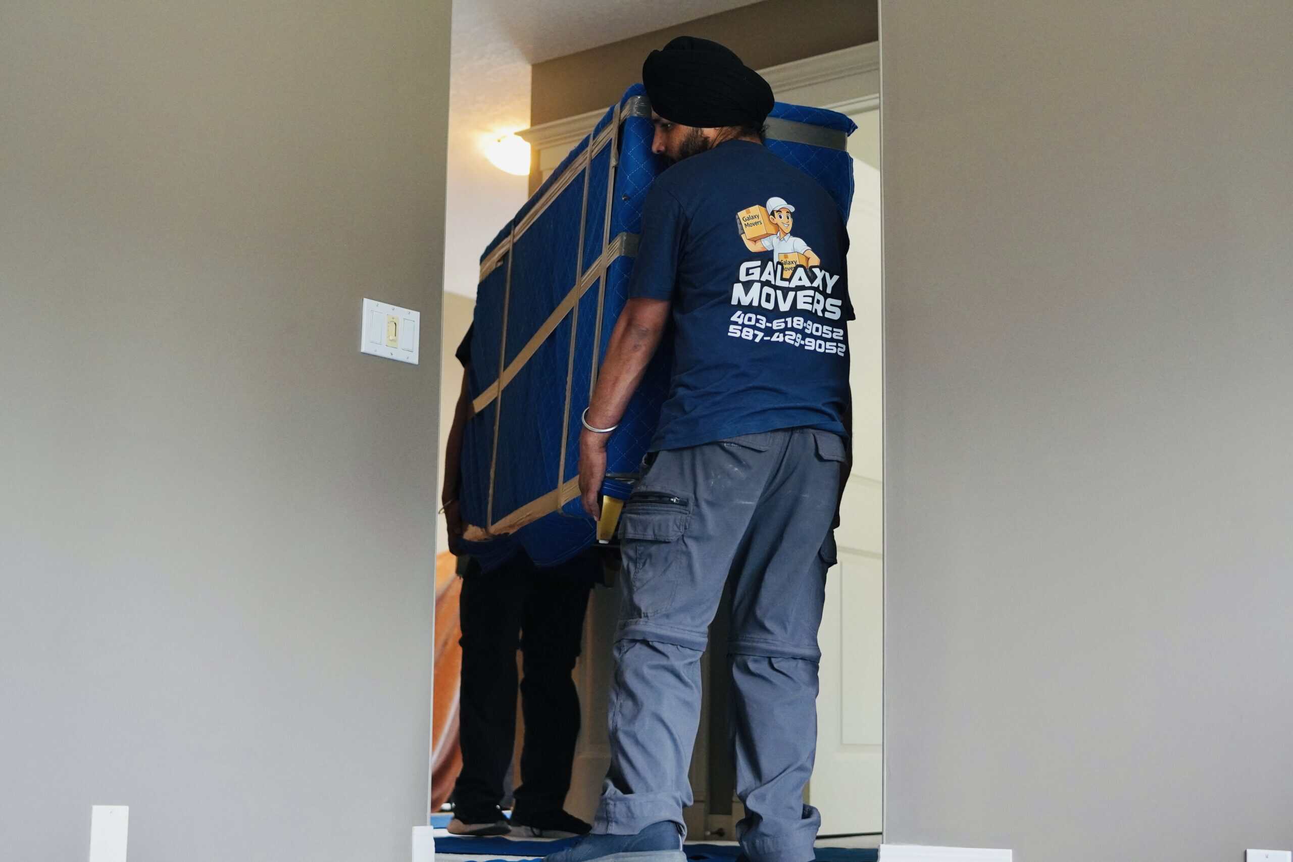 Mover carrying large furniture into a home for relocation.