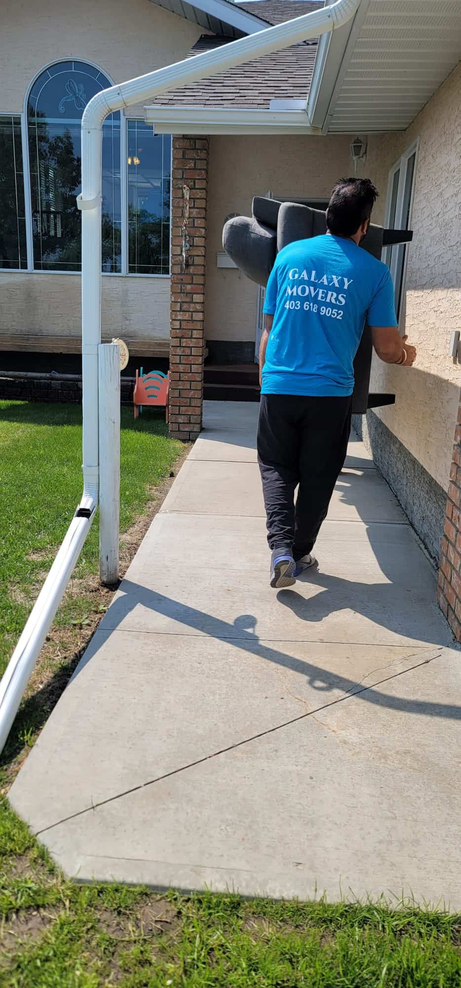 Galaxy Movers Calgary team member carrying items outside a house