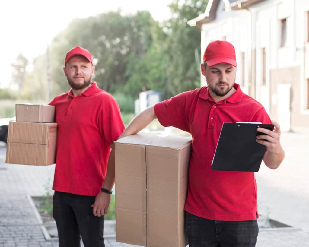 Two movers in red uniforms handling boxes outdoors in Calgary.